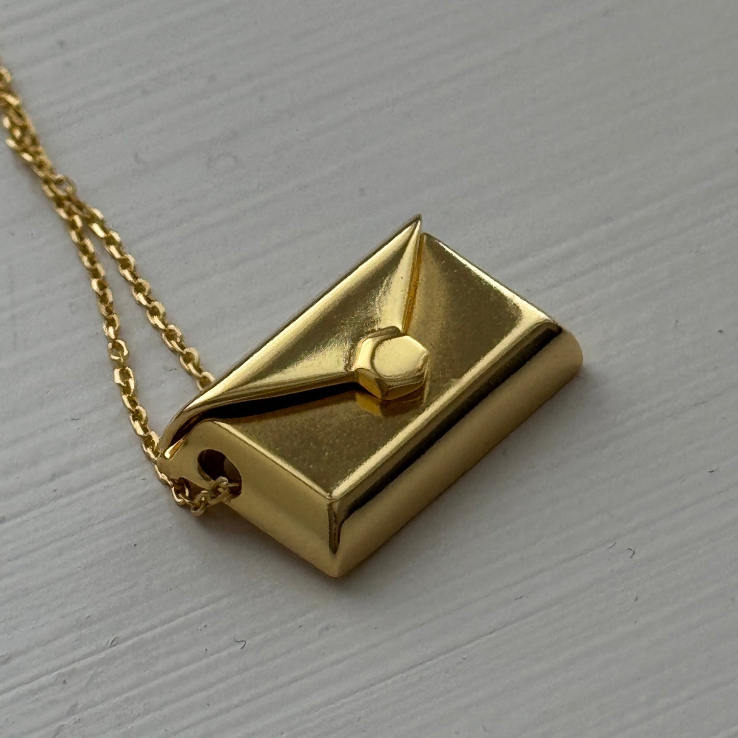 Gold plated envelope pendant that opens to reveal a hidden letter charm engraved with a personalized message.