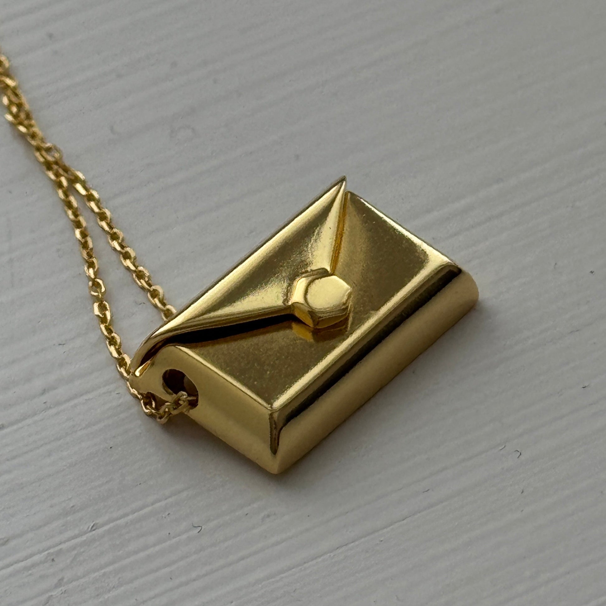 Gold plated envelope pendant that opens to reveal a hidden letter charm engraved with a personalized message.