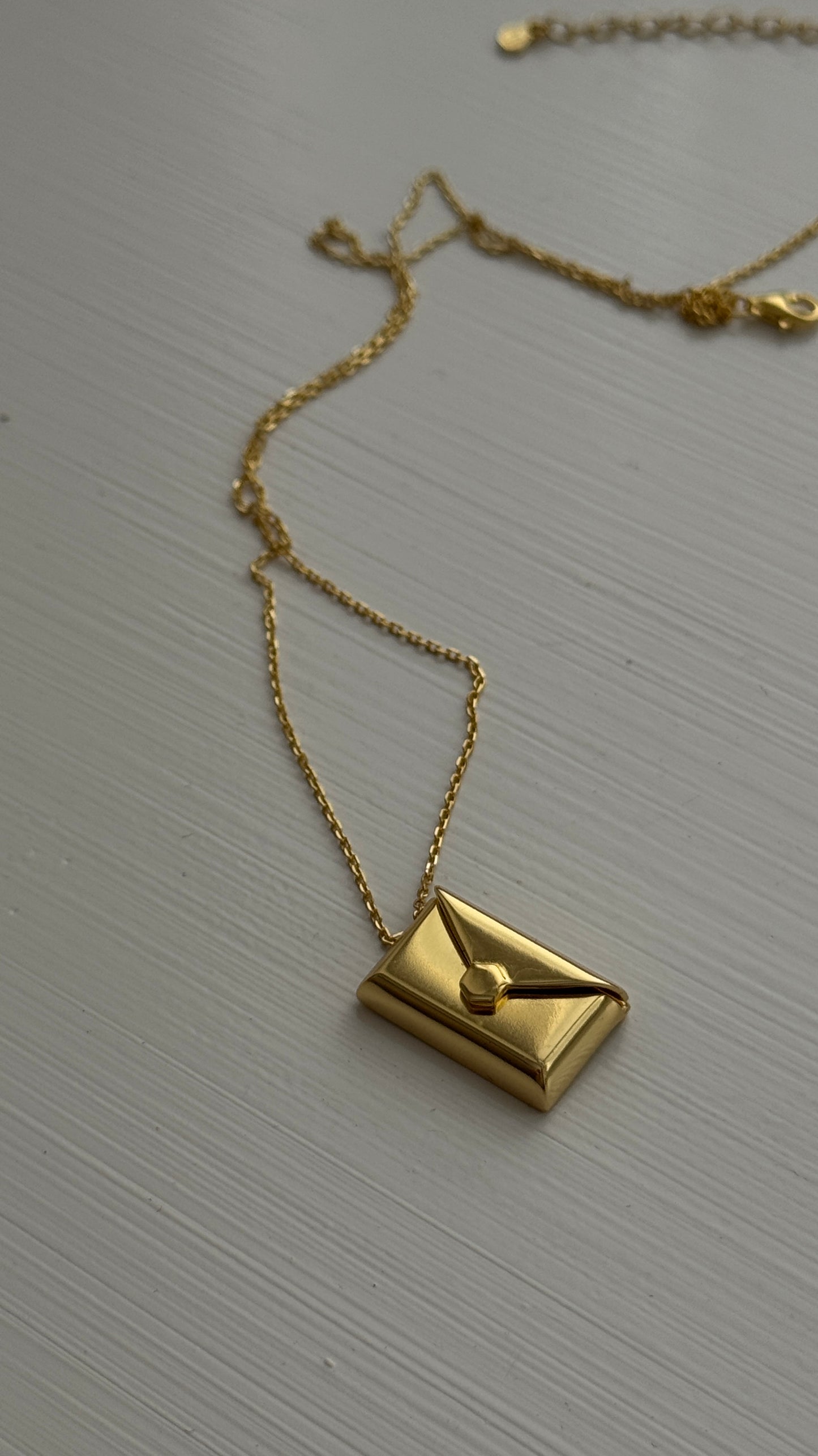 Gold envelope pendant that opens to reveal a hidden letter charm engraved with a personalized message.