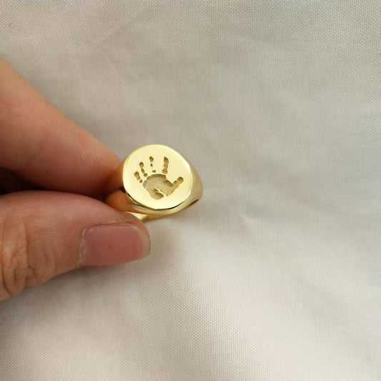Oval gold signet ring engraved with a personalized baby handprint