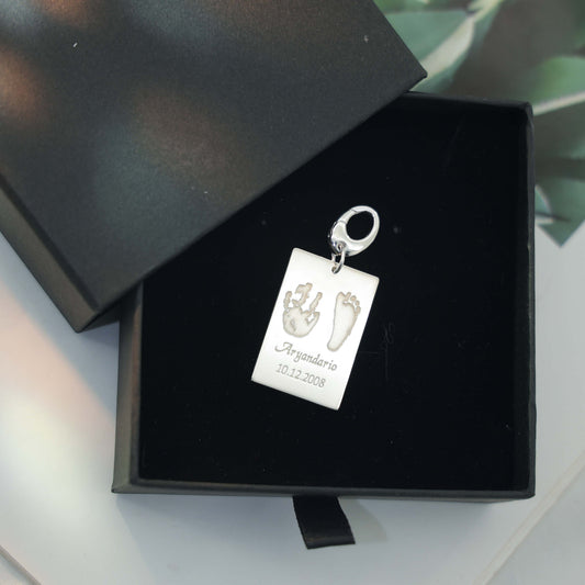 Sterling silver Ema Tag engraved with a child’s hand and footprint, name and birthdate attached to a keychain, symbolizing love and connection.