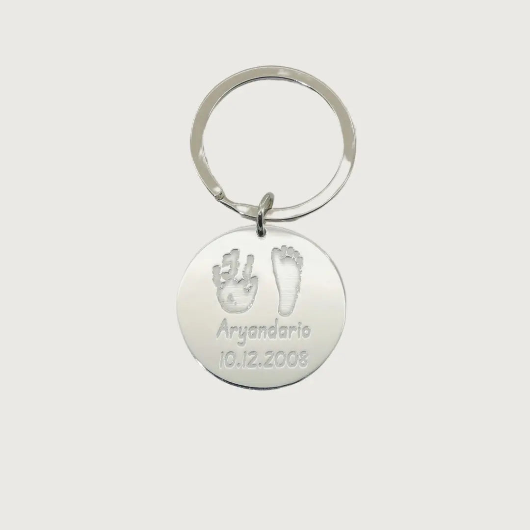 Sterling silver round Tina Tag engraved with a child’s handprint and footprint, name, and birthdate