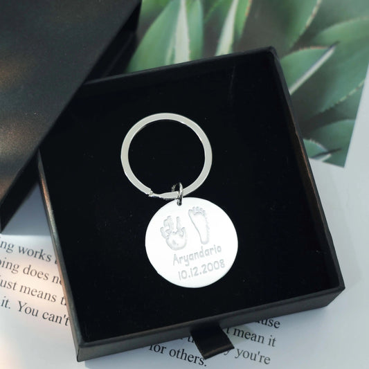 Sterling silver round Tina Tag engraved with a child’s handprint and footprint, name, and birthdate symbolizing love and connection.