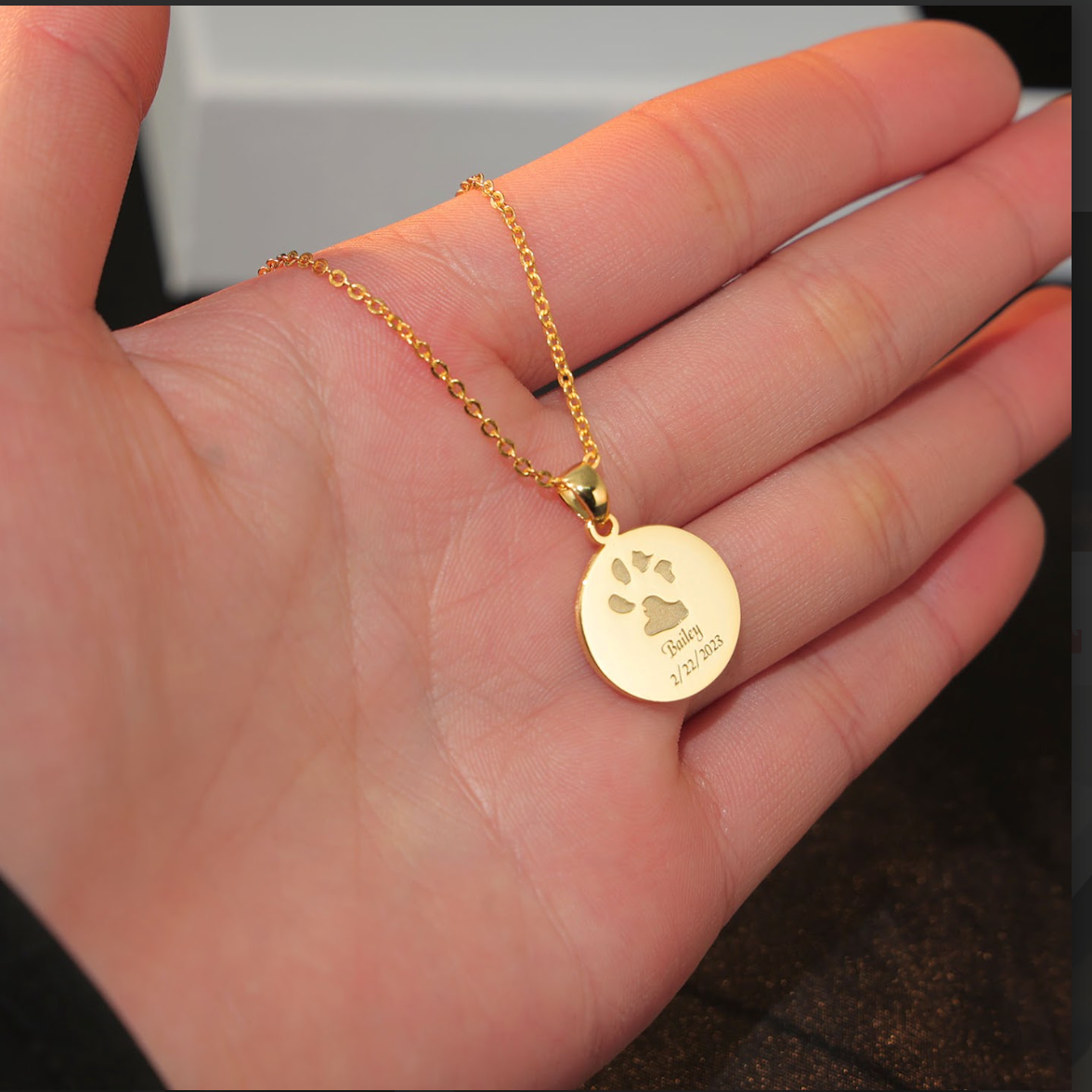 The gold plated round pendant with paw print, name, and date engraved on it by Chapters of Joy.