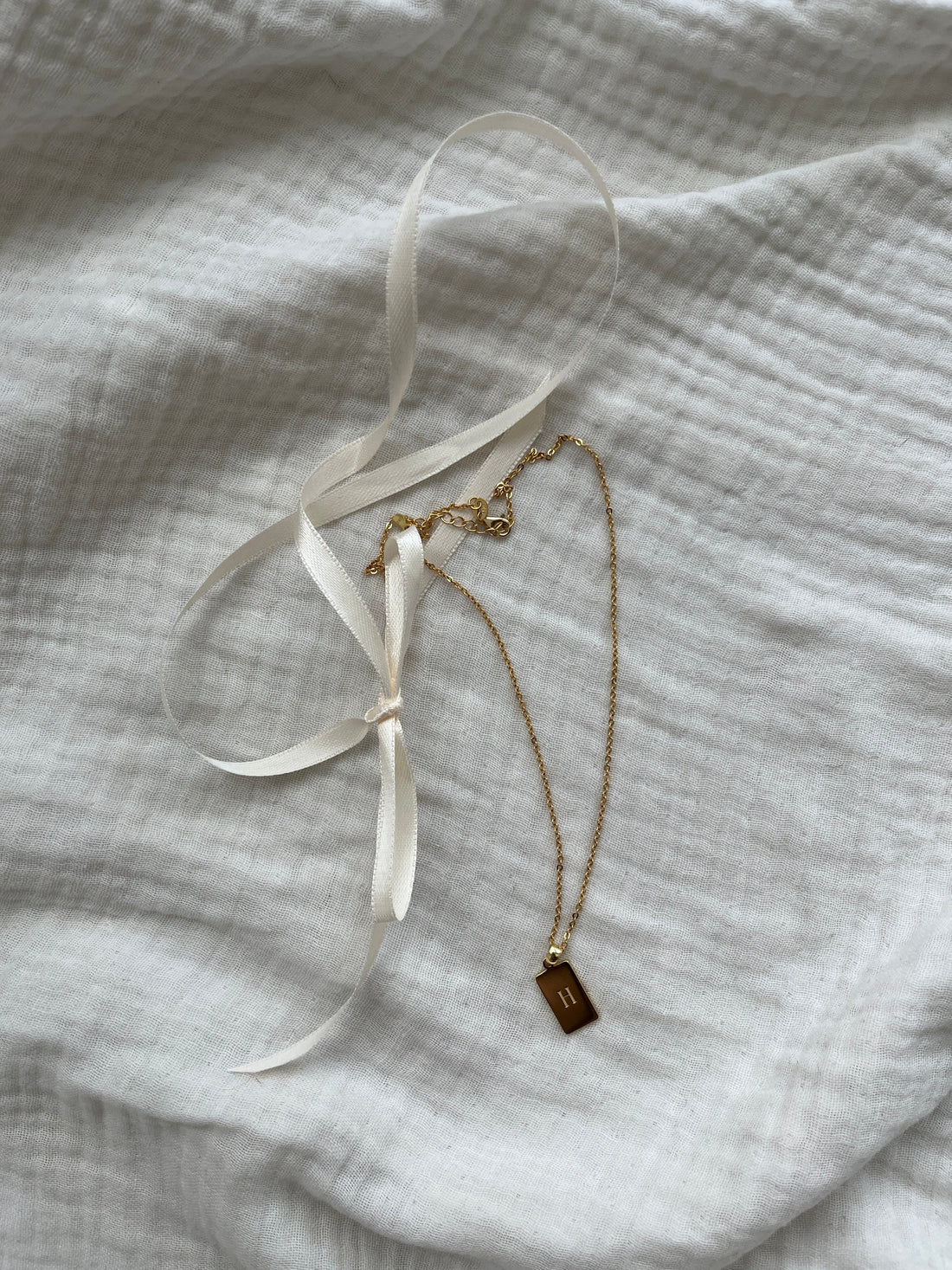 Gold-plated pendant necklace on linen cloth, affordable luxury