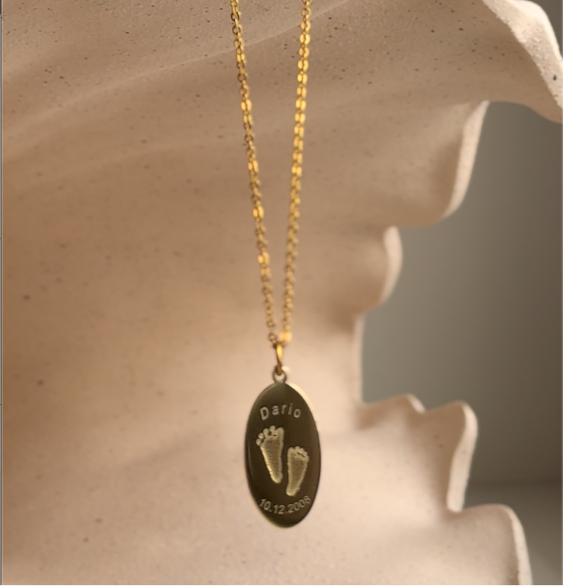 Engraved footprint, name, date of birth on an oval shape sterling silver, gold plated pendant.