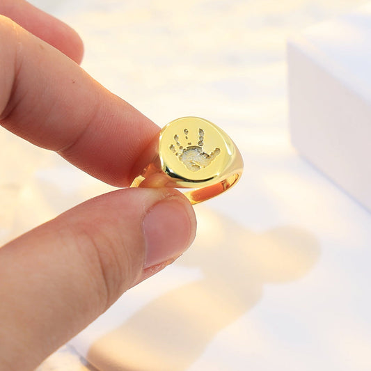 Gold oval signet ring engraved with a custom handprint engraving