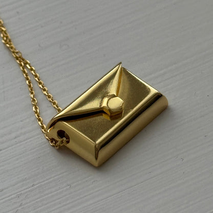Gold plated envelope pendant that opens to reveal a hidden letter charm engraved with a personalized message.