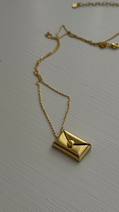 Gold envelope pendant that opens to reveal a hidden letter charm engraved with a personalized message.