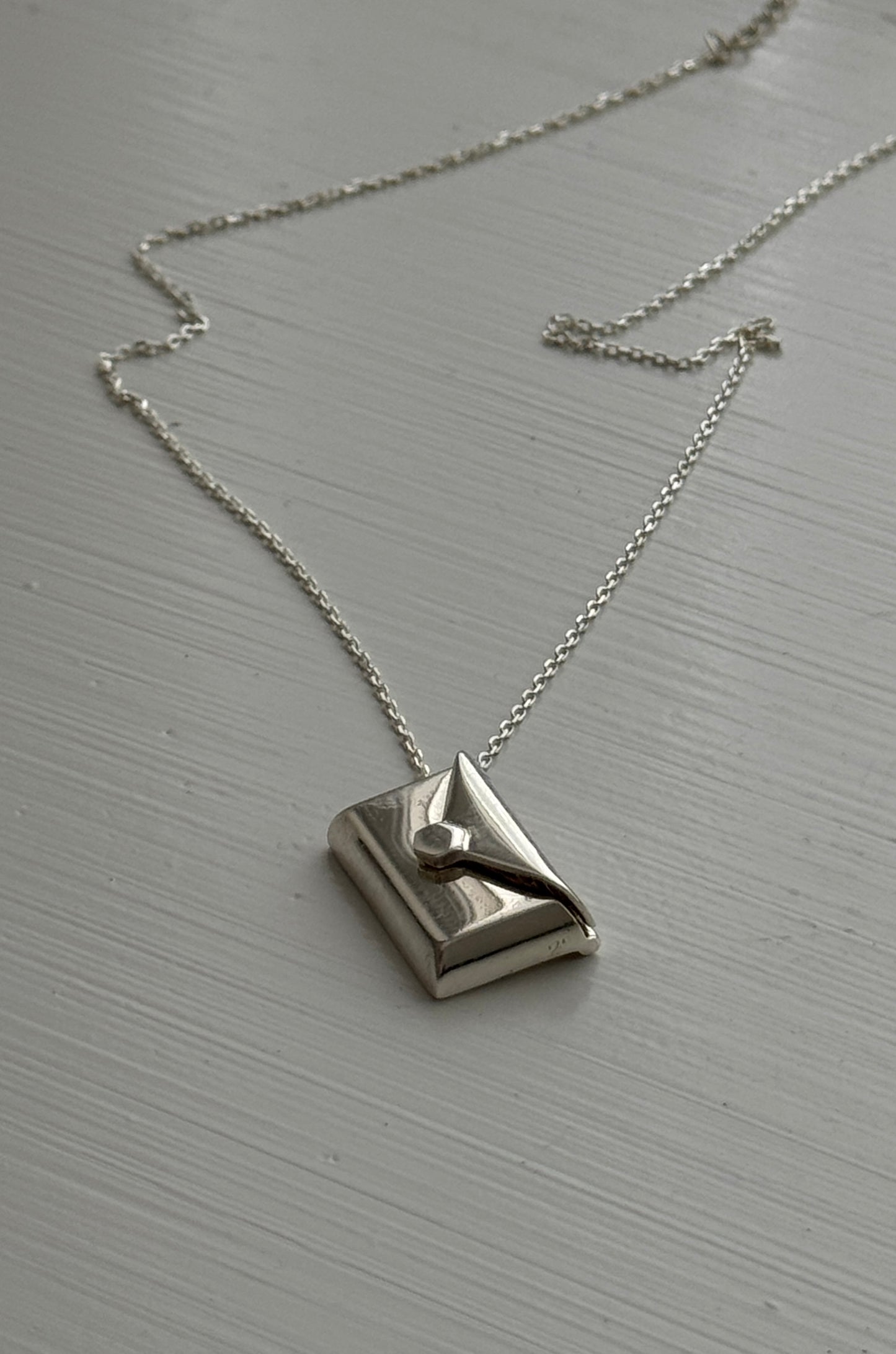 Silver envelope pendant that opens to reveal a hidden letter charm engraved with a personalized message.