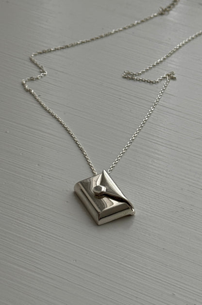Silver envelope pendant that opens to reveal a hidden letter charm engraved with a personalized message.