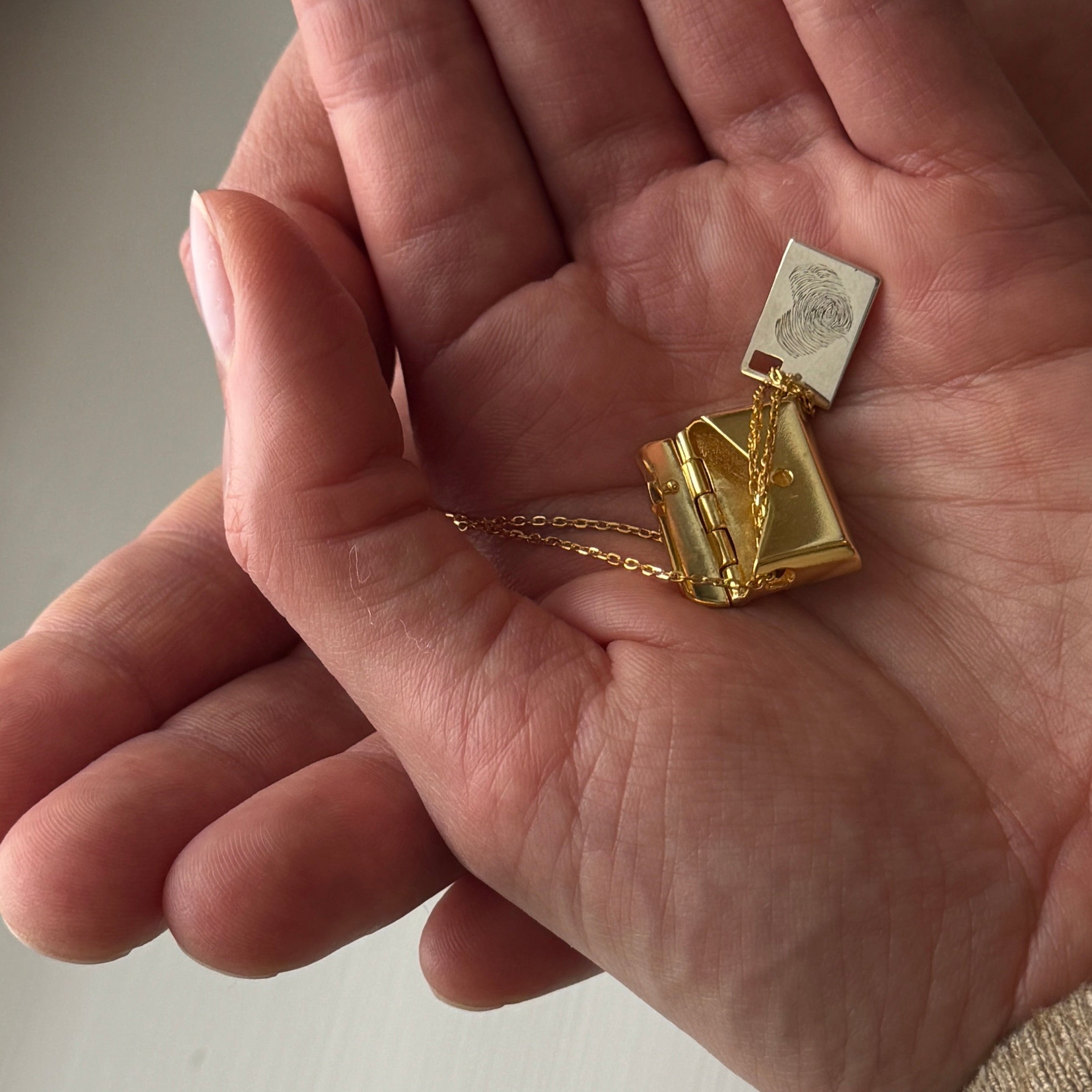 Envelope necklace and the secret message inside engraved with two fingerprints in heart shape.