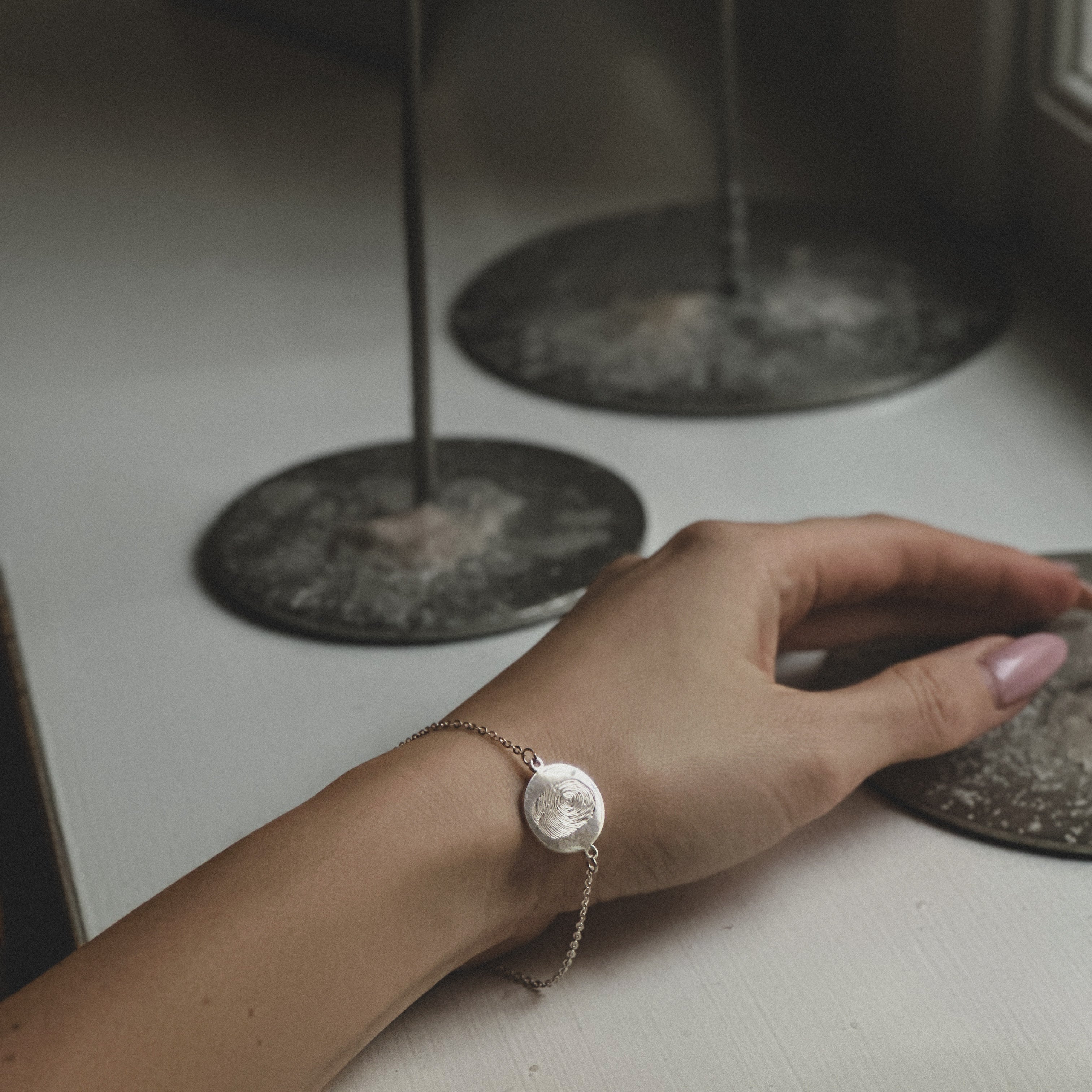 Hand wearing a sterling silverbracelet with a fingerprint engraved on it.