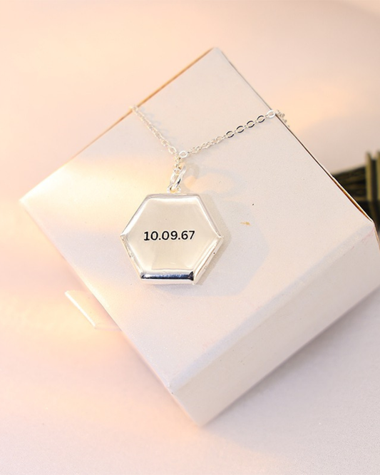 Maelle honeycomb locket necklace engraved with date 10.09.67 on the front, shown closed on a soft neutral jewelry box.