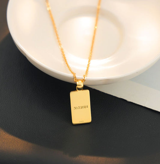 sterling silver gold plated rectangular pendant with a date engraved on the back of it.