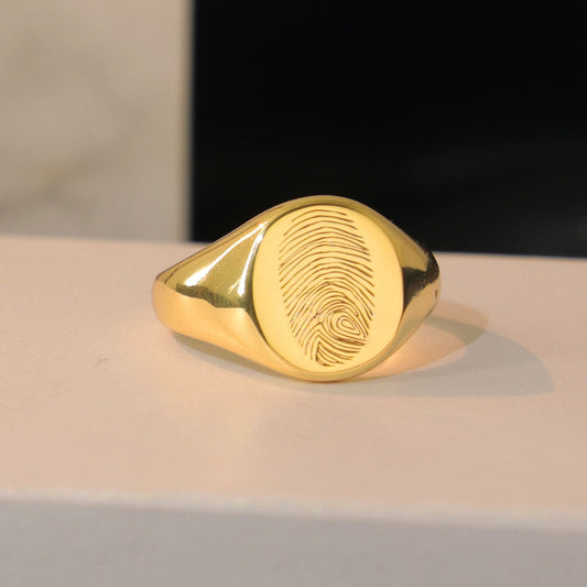 Oval gold signet ring engraved with a personalized fingerprint by Chapters of Joy