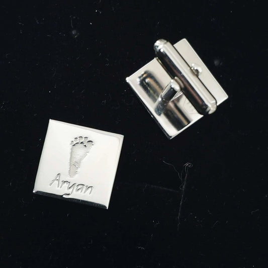 Personalized cufflinks with engraved baby footprint beside matching footprint artwork — custom keepsake cufflinks by Chapters of Joy.