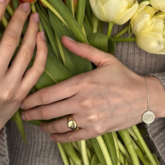 Personalized signet ring worn on hand holding flowers