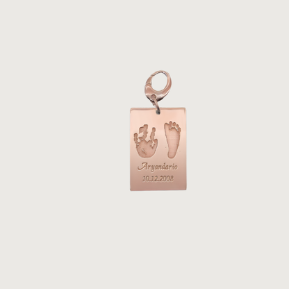 Rose Gold plated Ema Tag engraved with a child’s hand and footprint, name and birthdate attached to a keychain, symbolizing love and connection.