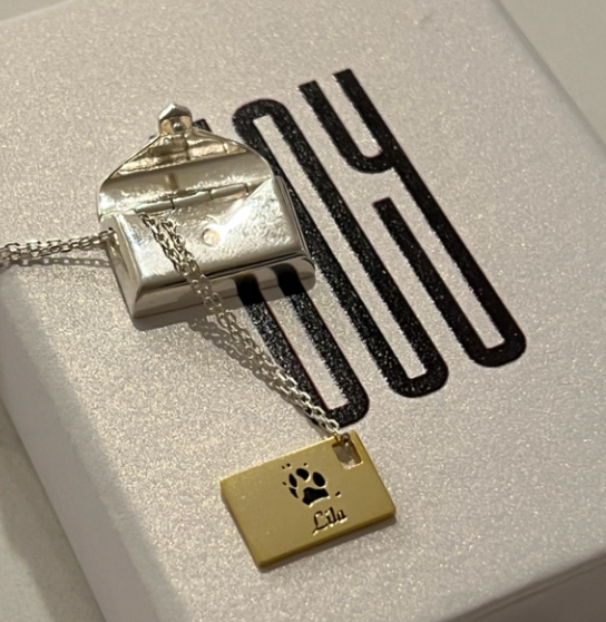 envelope locket with a letter gold tag featuring a paw print and name engraved on it 