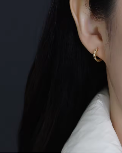 Sculpted gold  hoop earrings with gentle flowing curves  worn on the ear— Wavelet Hoops by Chapters of Joy.