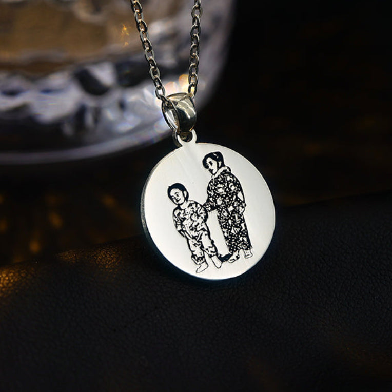 Silver necklace with a round pendant featuring engraved images on a dark background