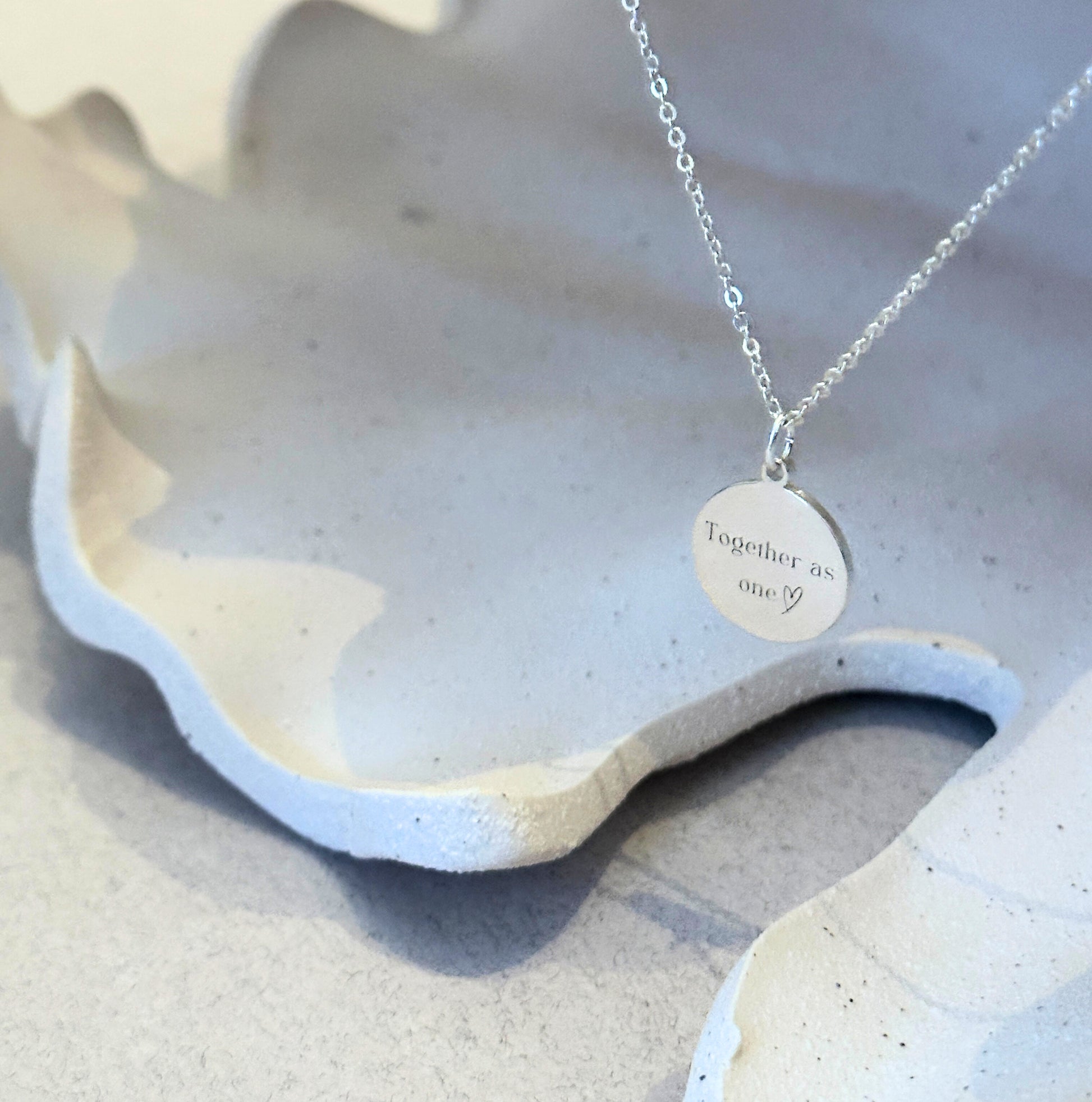 Personalized engraved pendant necklace shown on natural stone surface
