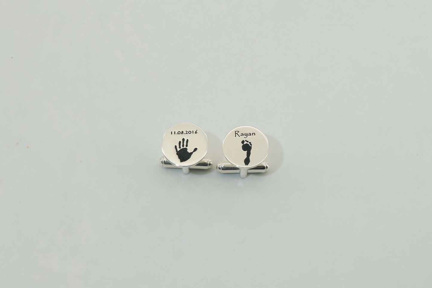 Round silver cufflinks engraved with a baby handprint and footprint — personalized cufflinks by Chapters of Joy.