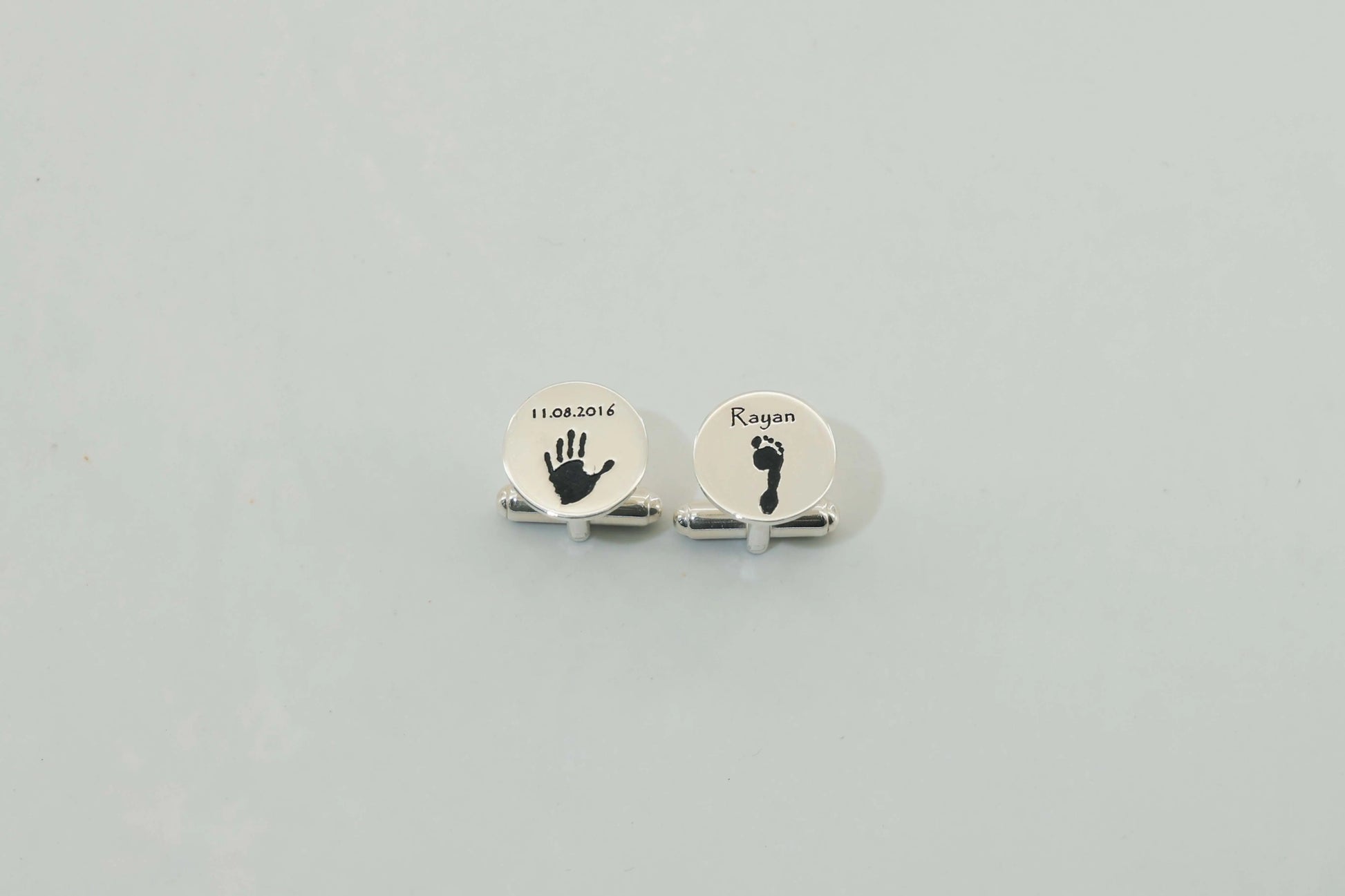 Round silver cufflinks engraved with a baby handprint and footprint — personalized cufflinks by Chapters of Joy.